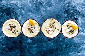 Top view of coconut halves with creamy dessert and toppings