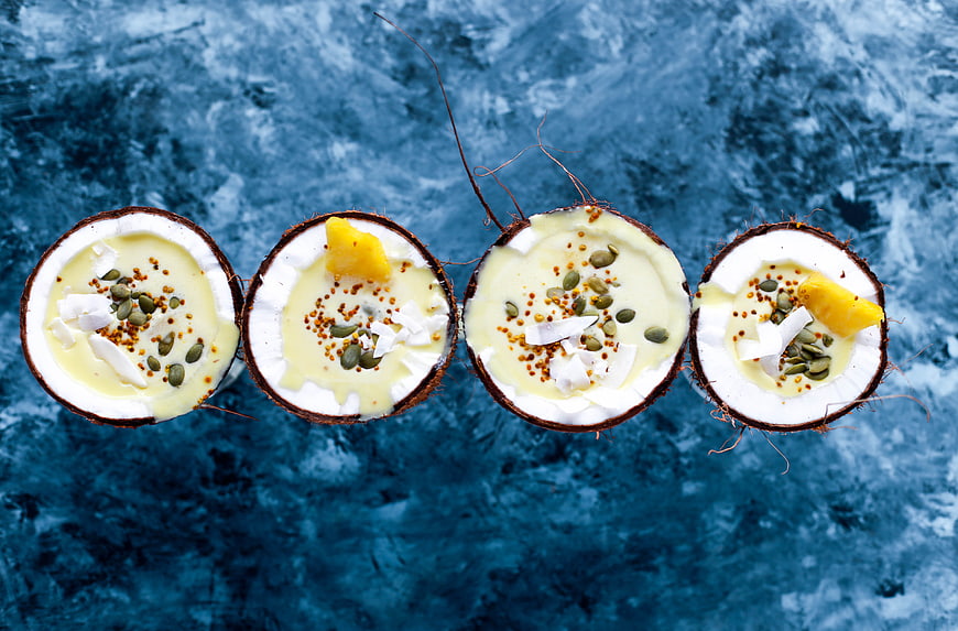 Top view of coconut halves with creamy dessert and toppings