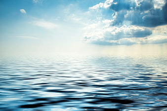 Serene Ocean Waves Under Bright Blue Sky with Clouds