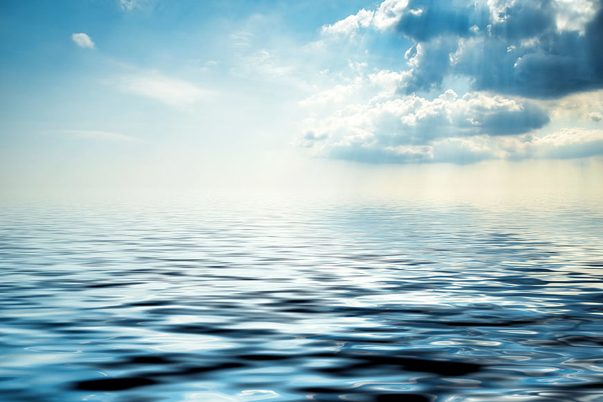 Serene Ocean Waves Under Bright Blue Sky with Clouds