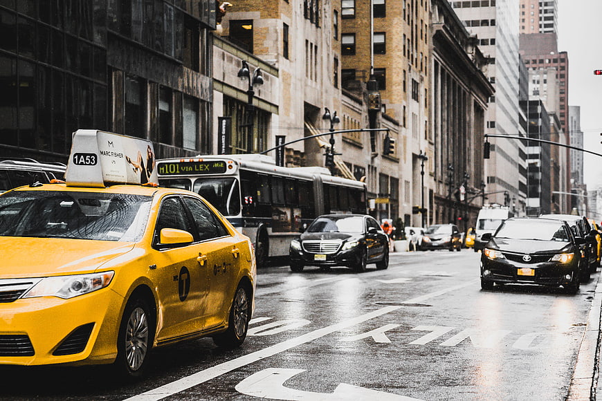 Yellow taxi cab driving on wet city street