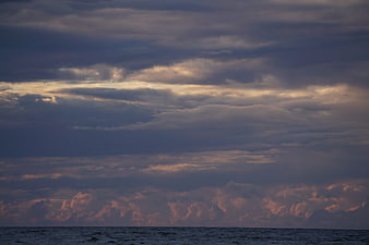 Dramatic sunset clouds over dark ocean waves