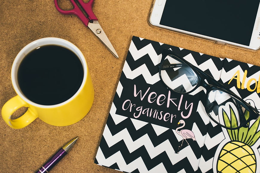 Flat Lay of Weekly Planner, Coffee, and Office Supplies