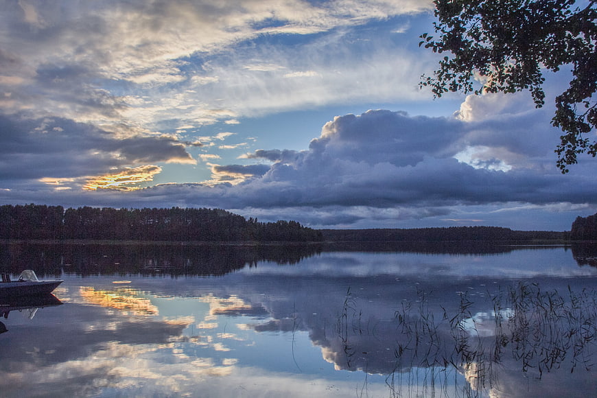 Serene Lake Sunset with Dramatic Clouds and Forest Reflection