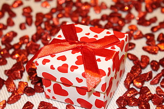 White gift box with red hearts and shiny confetti