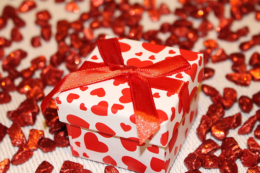 White gift box with red hearts and shiny confetti