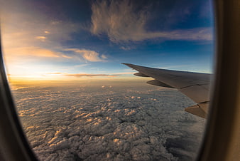 Airplane wing view over clouds at sunset