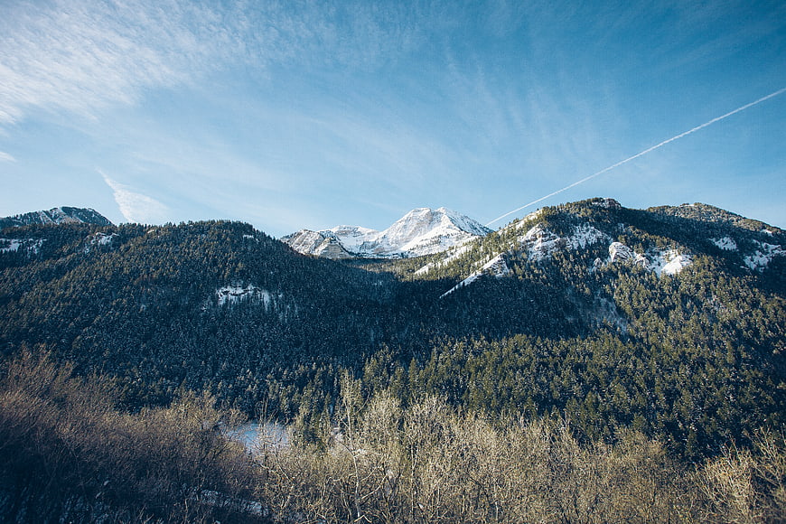 Snowy Mountain Peaks and Forested Slopes Under Blue Sky