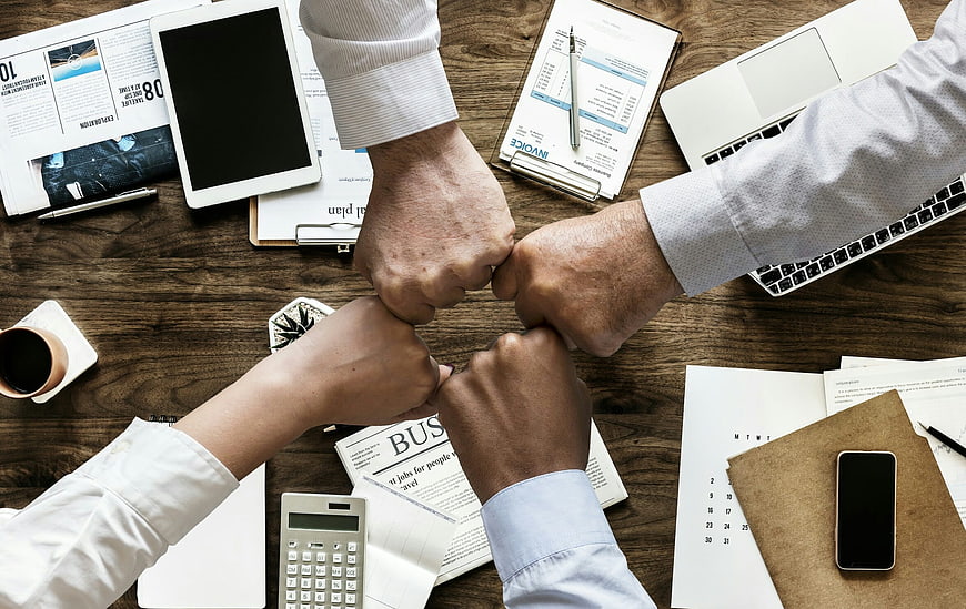 Diverse business team fist bumping over office desk