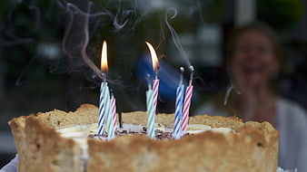 Birthday cake with lit candles and blurred smiling woman