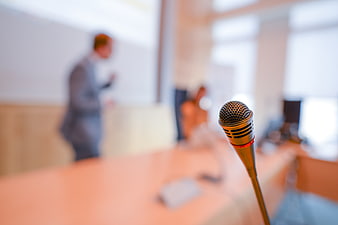 Microphone in foreground with blurred business presentation background