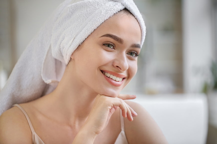 Happy woman with towel on head smiling after shower