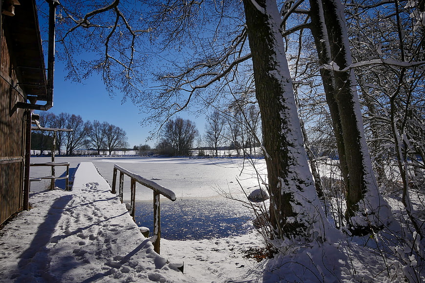 Snowy wooden dock on a frozen lake in winter