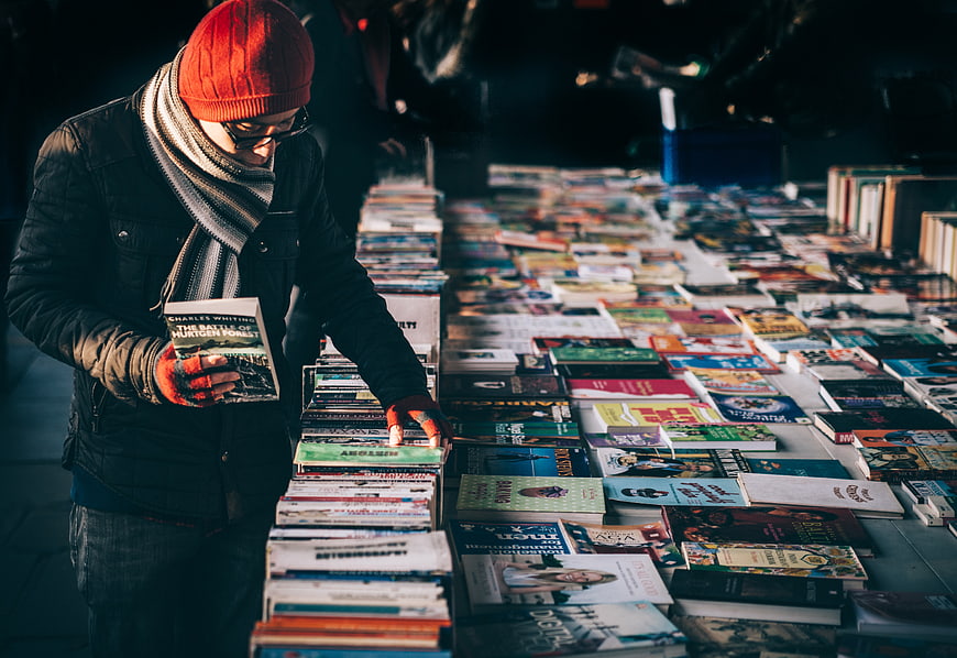 Man browsing books at outdoor market stall