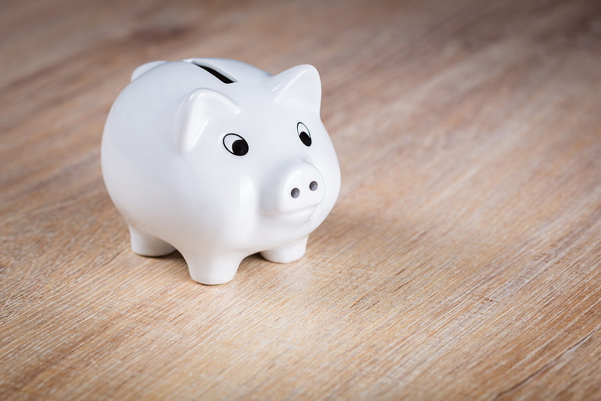 White ceramic piggy bank on wooden table background