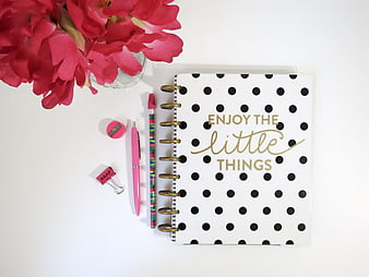 Flat lay of polka dot planner with pink flowers and stationery