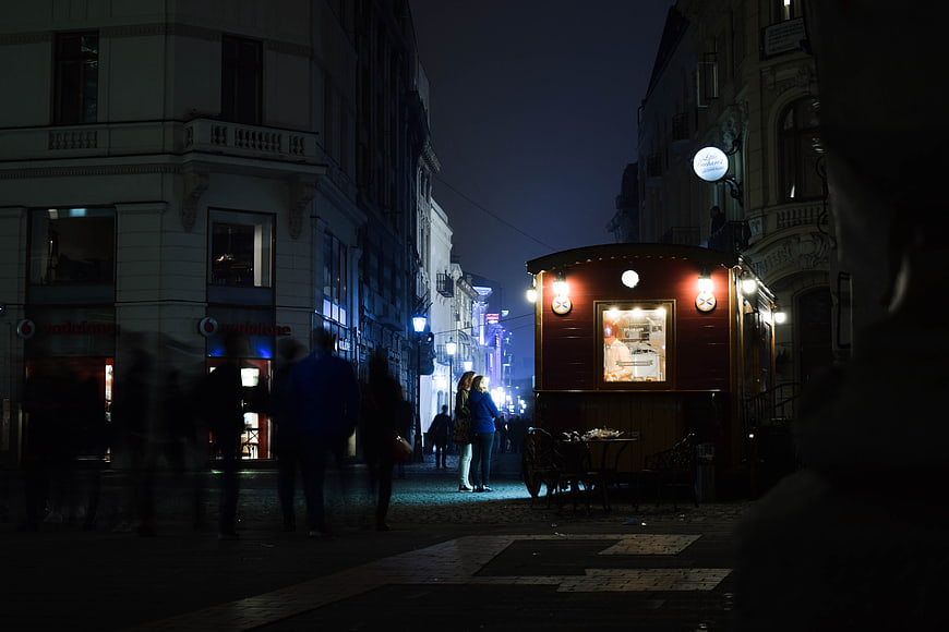 Night street scene with food cart and pedestrians in Bucharest