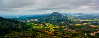 Panoramic mountain landscape with tilt-shift effect and green valleys