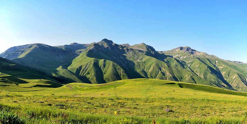 Lush Green Mountain Landscape With Blue Sky And Rolling Pastures