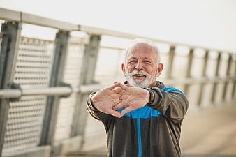Senior man stretching arms outdoors on bridge