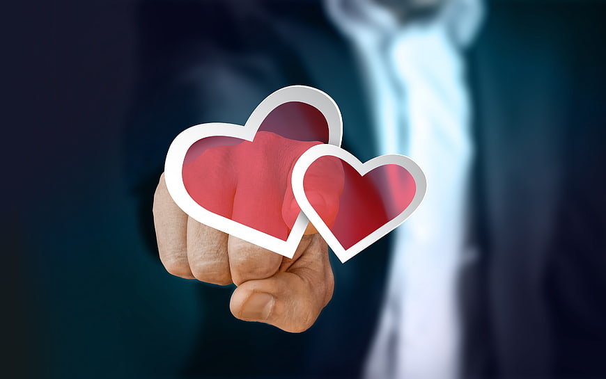 Businessman hand pressing red heart button symbolizing love and compassion