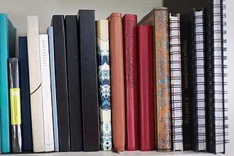 Colorful Books and Notebooks on a White Shelf