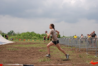 Woman Running in Muddy Obstacle Course Race