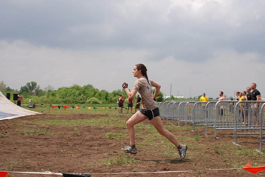 Woman Running in Muddy Obstacle Course Race