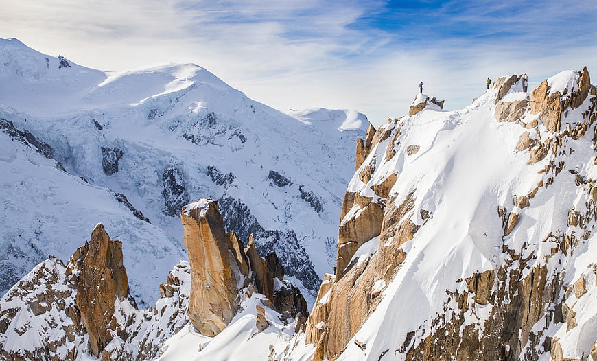 Hikers on Snowy Mountain Ridge with Blue Sky