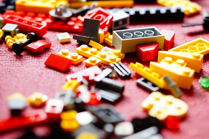Scattered colorful plastic building blocks on red textured background
