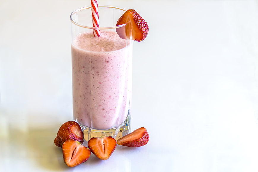 Fresh Strawberry Smoothie in Glass with Straw and Fruit