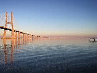 Long cable-stayed bridge over calm water at sunrise