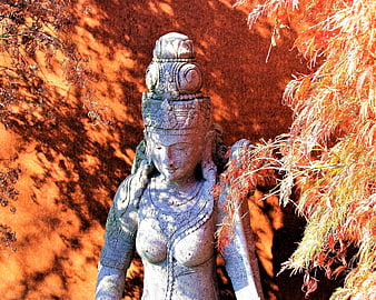 Stone Statue of Asian Deity with Autumn Foliage Background