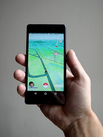 Hand holding smartphone playing Pokemon Go game