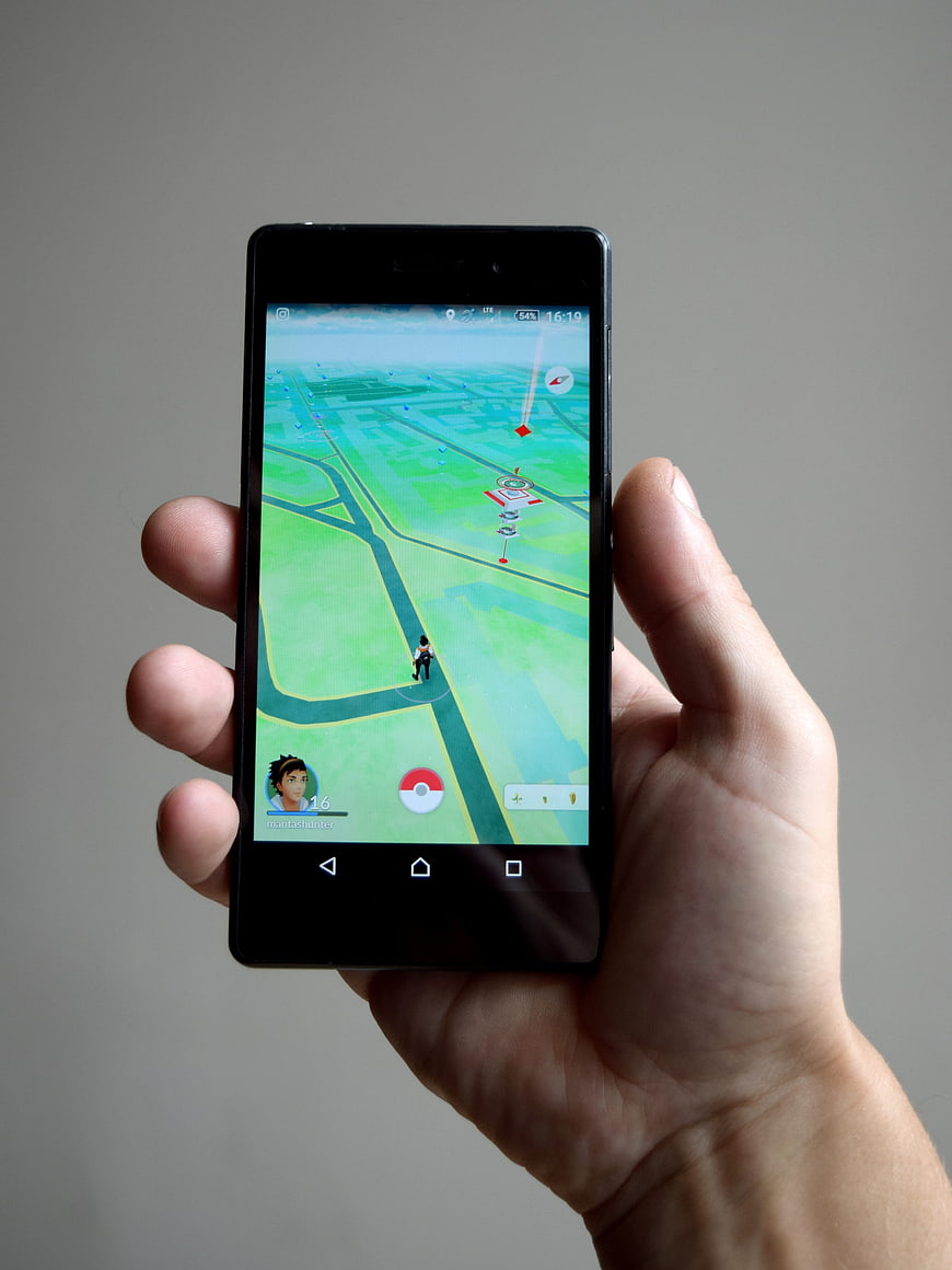 Hand holding smartphone playing Pokemon Go game