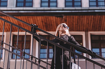 Stylish blonde woman in sunglasses on urban staircase