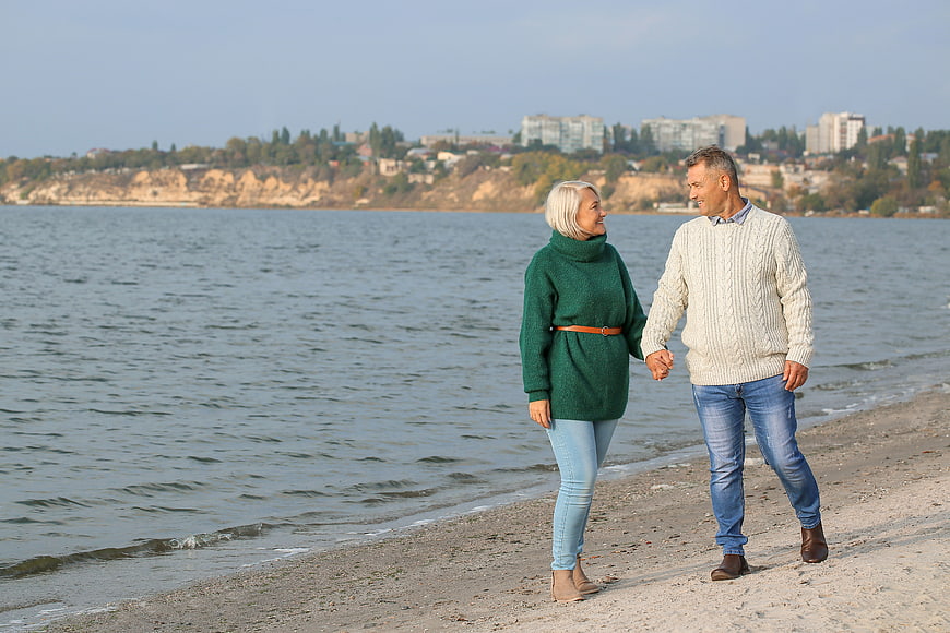 Happy Senior Couple Walking Hand in Hand on Beach