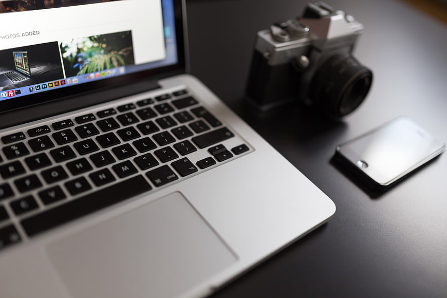 Laptop, Vintage Camera, and Smartphone on Dark Desk
