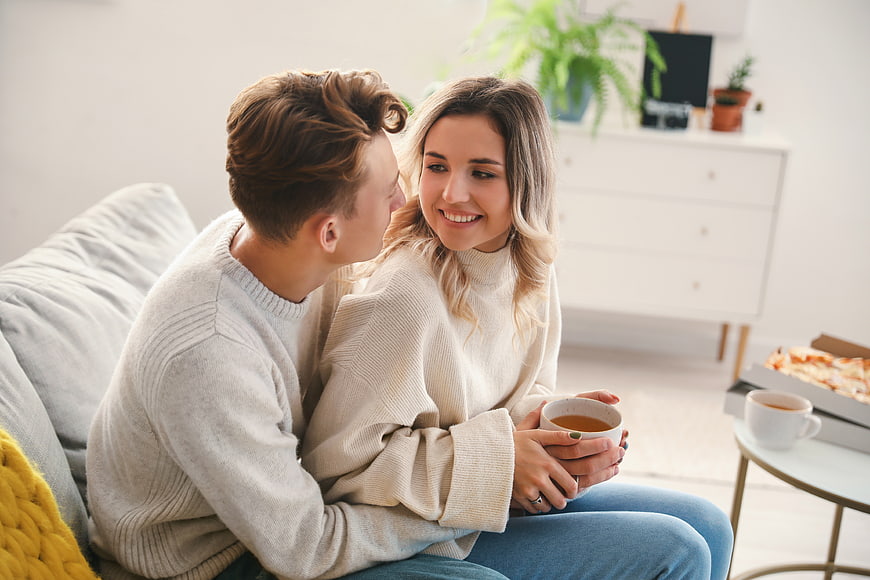 Happy couple relaxing at home with coffee and pizza
