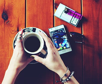 Top view of hands holding coffee cup on wooden table