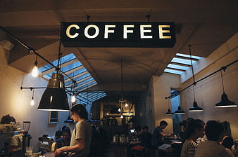 Interior of a busy coffee shop with hanging sign and customers