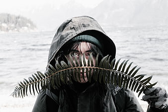 Woman in Hoodie Holding Fern Leaf by Lake