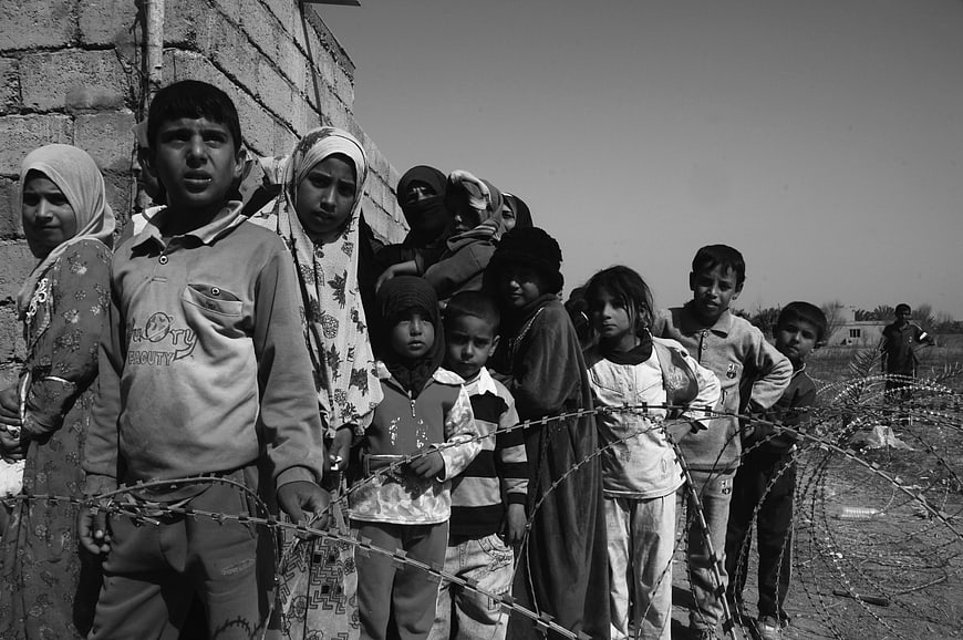 Black and white photo of children and women behind barbed wire