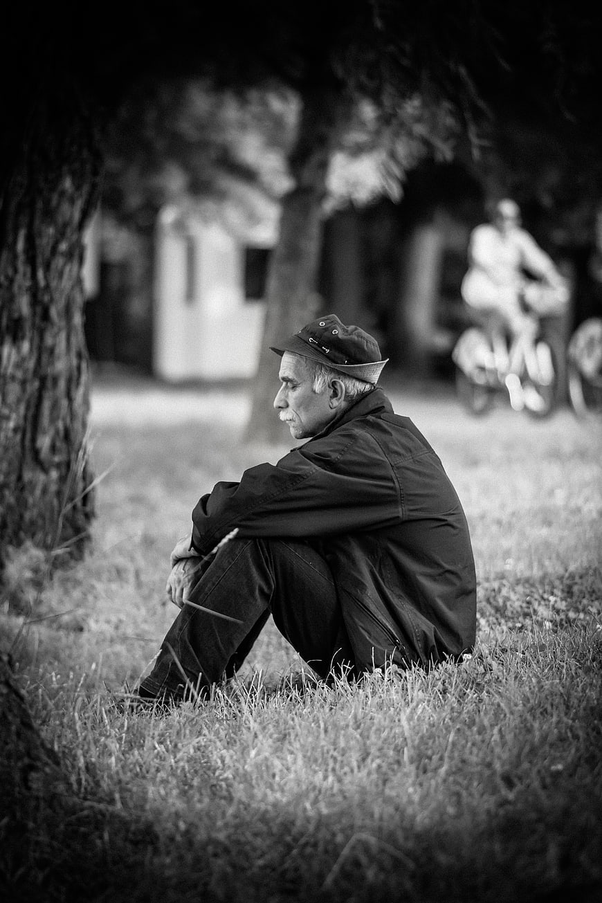 Contemplative Senior Man Sitting on Grass in Black and White
