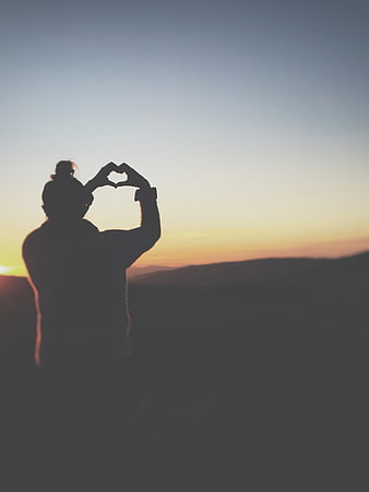 Silhouette of Woman Making Heart Shape at Sunset