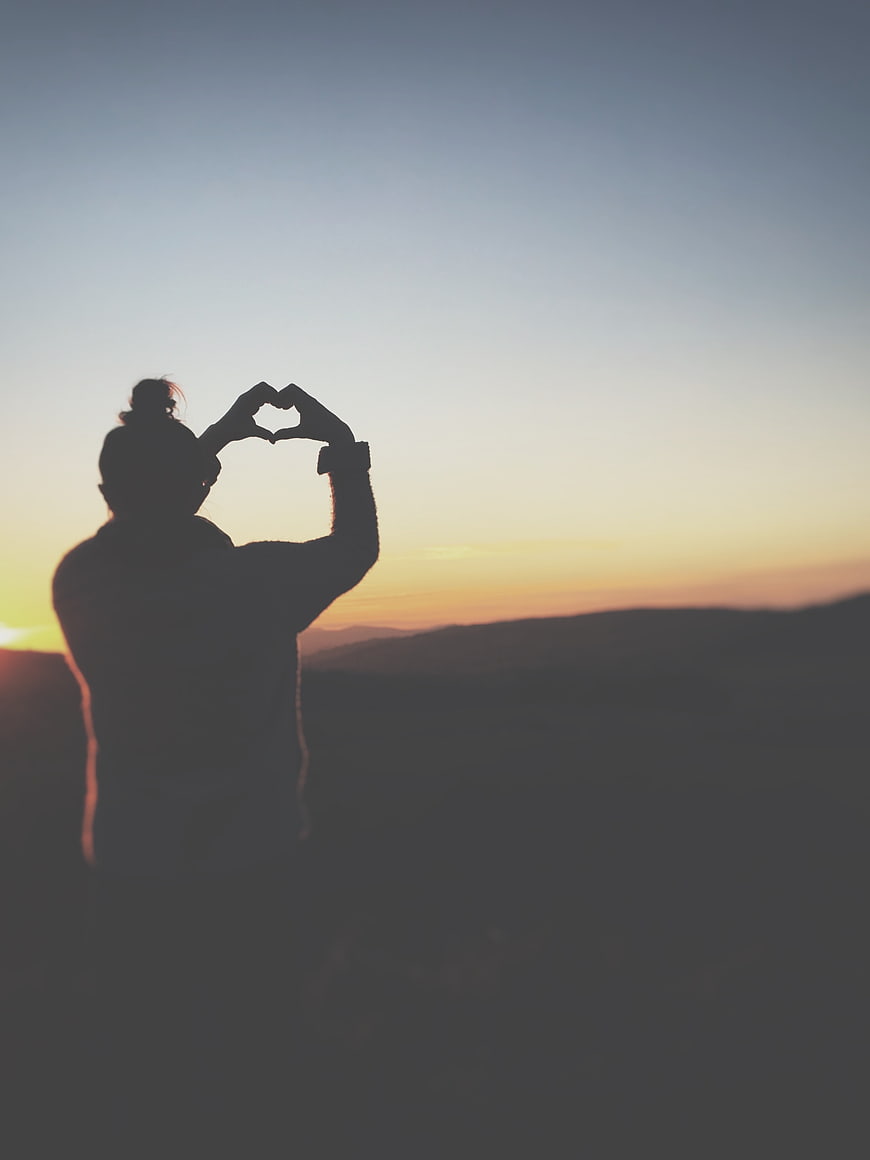 Silhouette of Woman Making Heart Shape at Sunset