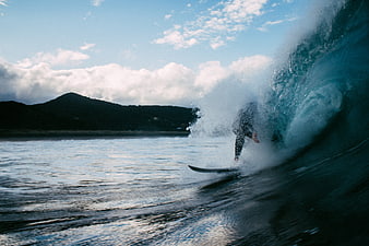 Surfer riding a wave with mountain backdrop