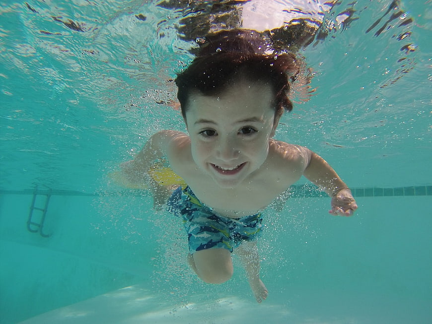 Happy boy swimming underwater in a pool