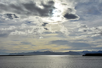Dramatic Cloudy Sky Over Ocean and Distant Mountains