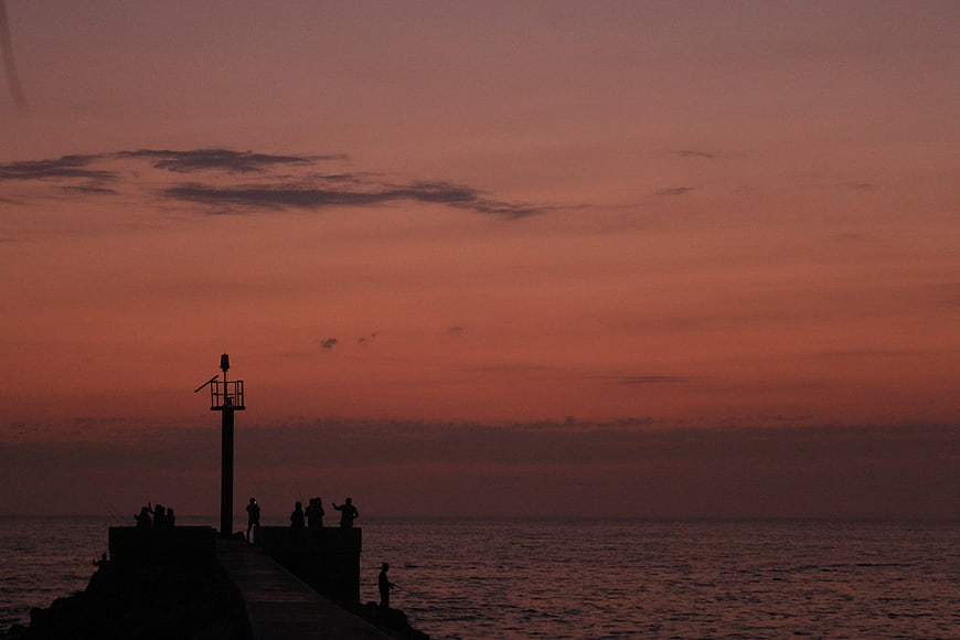 Silhouettes of people on a pier at sunset